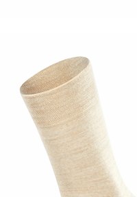 Chaussette beige au toucher doux, avec un bord côtelé et une forme effilée. Fabriquée à partir d'un matériau léger et respirant.