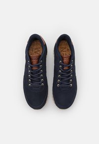 Baskets en daim bleu marine avec accents en cuir marron, œillets dorés et semelles intérieures en liège texturé. Design classique à lacets avec semelle en caoutchouc.