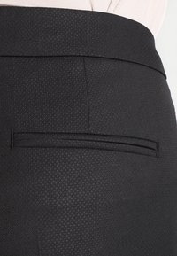 Sorte bukser med et glat, tekstureret stof med et subtilt mønster, slim fit og en enkelt, diskret baglomme.