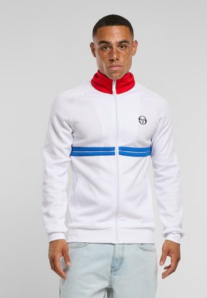 Hvit zip-up treningsjakke med rød høy krage, blå horisontale striper over brystet og en liten logo på venstre side.