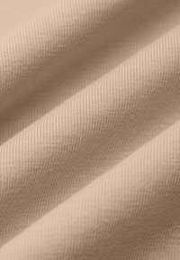 Jasnoróżowa ribbed tkanina o miękkiej teksturze, z ukośnymi liniami ściegów i subtelnym rozciągnięciem, ułożona w delikatne fałdy.