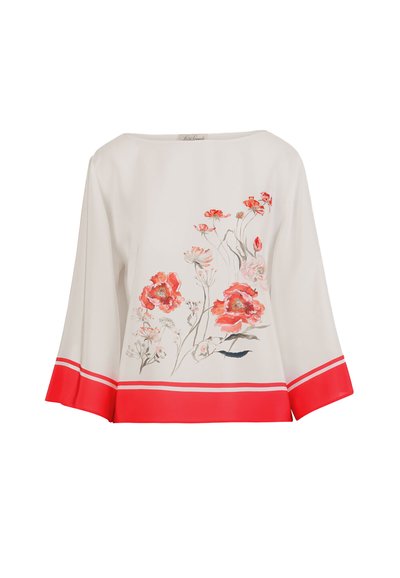 Blouse blanche à manches longues avec imprimé floral rouge sur le devant et larges poignets rouges avec des rayures blanches aux manches et à l'ourlet.