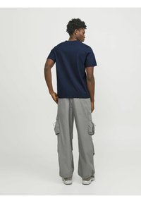 Camiseta de algodón de color navy con cuello redondo, combinada con pantalones cargo gris de corte holgado que cuentan con múltiples bolsillos y puños con cordón.
