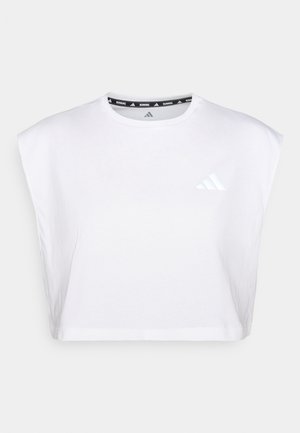 White cropped athletic shirt made of soft cotton. Features a round neckline and short, wide sleeves. Displays a reflective Adidas logo on the chest.