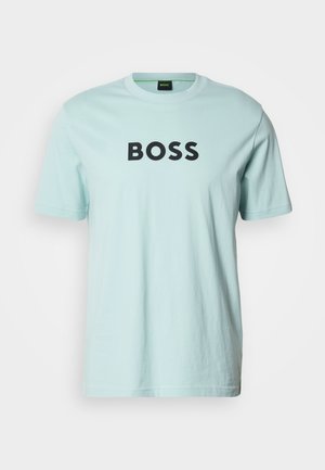 Lys blå bomulls-T-skjorte med rund hals og korte ermer. Har ordet "BOSS" i fete svarte bokstaver over brystet.