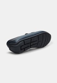 Pantof de piele neagră cu talpă plată din cauciuc, având un model texturat pentru aderență. Designul este elegant, fără elemente metalice sau accente vizibile.