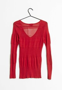 Červený pletený svetr s dlouhými rukávy, s výstřihem do V a texturovanými žebrovanými vzory po celém svetr, zavěšený na ramínku.