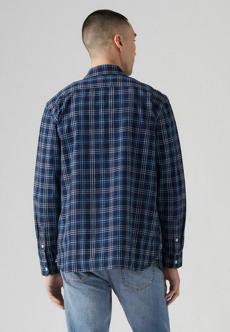 Marineblaues Karoshirt mit langen Ärmeln, Knopfmanschetten und klassischem Kragen. Mit hellblauem und weißem Gittermuster. Aus Baumwollstoff.