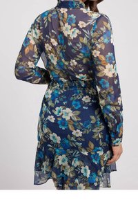 Abito floreale in tessuto trasparente con una base blu scuro e grandi fiori blu e crema. Presenta un colletto e un dettagliato punto vita arricciato.