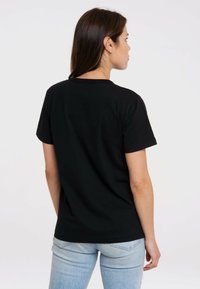 Black cotton t-shirt with short sleeves and a crew neckline, featuring a smooth texture and relaxed fit, worn with light blue jeans.