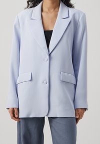 Světle modrý blazer vyrobený z hladkého materiálu, s jednoprstým zapínáním, dvěma předními kapsami a uvolněným střihem.