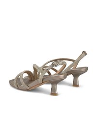Metalen gouden open hak sandalen met gekruiste banden en strass accenten. Vierkante neus en een lage, flared hak. Soepele textuur.