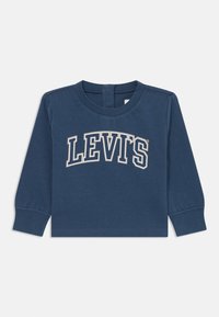 Pitkähihaine sininen T-paita, joka on valmistettu puuvillasta ja jossa on kaareva valkoinen "LEVI'S" -logo rintamuksessa sekä pyöreä kaula-aukko.