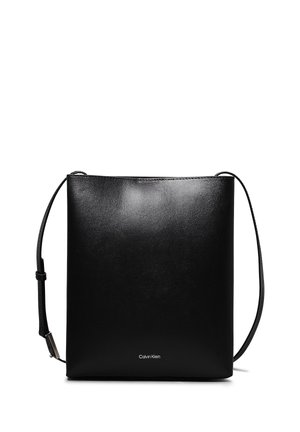 Bolso bandolera negro de Calvin Klein con diseño minimalista, textura suave y correa de hombro ajustable sobre un fondo blanco.