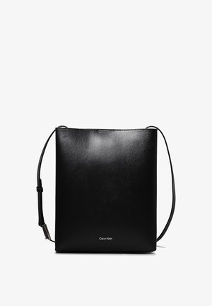 Czarna torebka na ramię Calvin Klein o minimalistycznym designie, gładkiej fakturze i regulowanym pasku na ramię na białym tle.