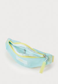 Rucsac de fanny de culoare albastru deschis, cu o textură netedă, fermoar galben și o etichetă mică atârnând. Are un compartiment cu fermoar și un design elegant.