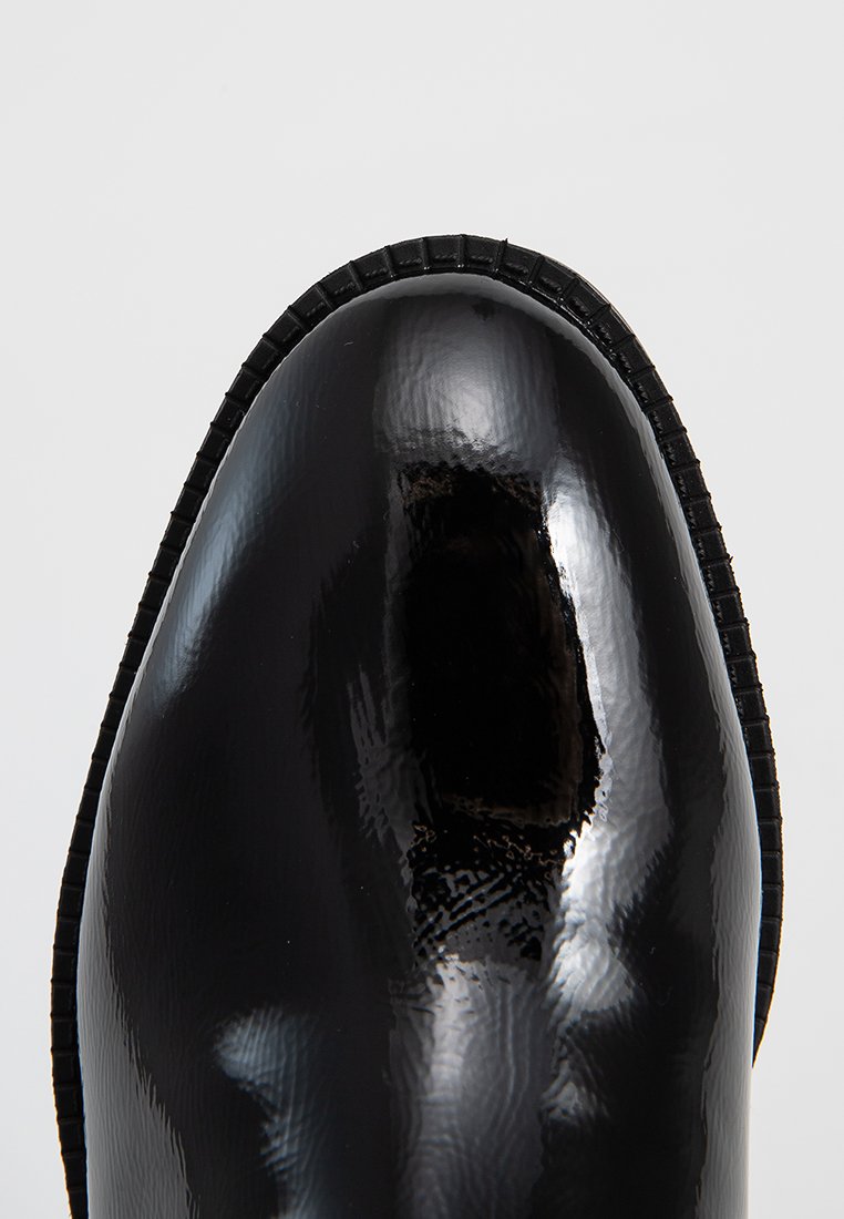 Stivaletto in pelle verniciata nera con punta rotonda, superficie texturizzata e suola in gomma scanalata. Finitura liscia con riflessi delicati.