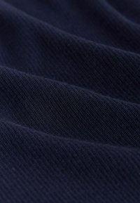 Close-up van donkerblauwe geribbelde stof met zichtbare parallelle textuurlijnen en zachte plooien.