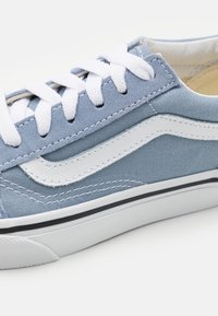 Sneaker in tela azzurro chiaro con lacci bianchi e striscia laterale. Presenta una superficie testurizzata, suola intermedia nera e suola in gomma.