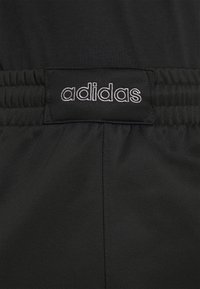 Černé sportovní šortky s elastickým pasem a bílým vyšitým logem "adidas". Hladká tkanina s jemnými texturovými detaily.