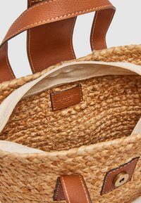 Vävd halmhandväska med bruna läderhandtag och detaljer. Har en beige tygfoder och ett märkt läderpatch inuti.