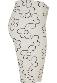 White floral-patterned shorts with black outlines, stretchy fabric, fitted design, mid-rise waist, and smooth texture.
