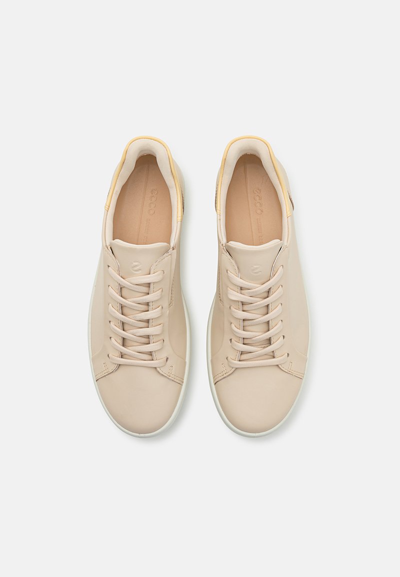 Beige Leder-Sneaker mit weißen Gummisohlen, runder Zehenform, Schnürdesign und einem dezenten gelben Akzent an der Ferse.