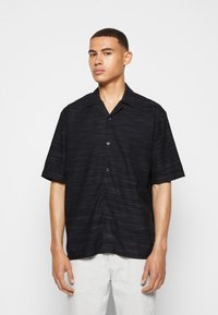 Black short-sleeve shirt with a textured striped pattern, featuring a button-front closure and a classic collar.