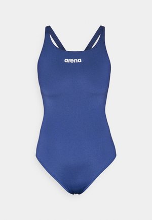 Bañador de una pieza en azul marino con tirantes finos y una textura suave. Presenta un logo blanco de "arena" en el pecho.