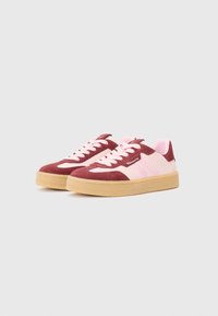 Sneaker in suede bordeaux e rosa, con una spessa suola in gomma, pannelli a contrasto e lacci piatti, caratterizzati da una texture liscia e un design sportivo.