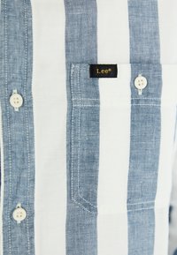 Blau-weiß gestreiftes Hemd mit einer Tasche, aus einem Stoff mit glatter Textur. Mit Lee®-Logo-Tag und weißen Knöpfen.