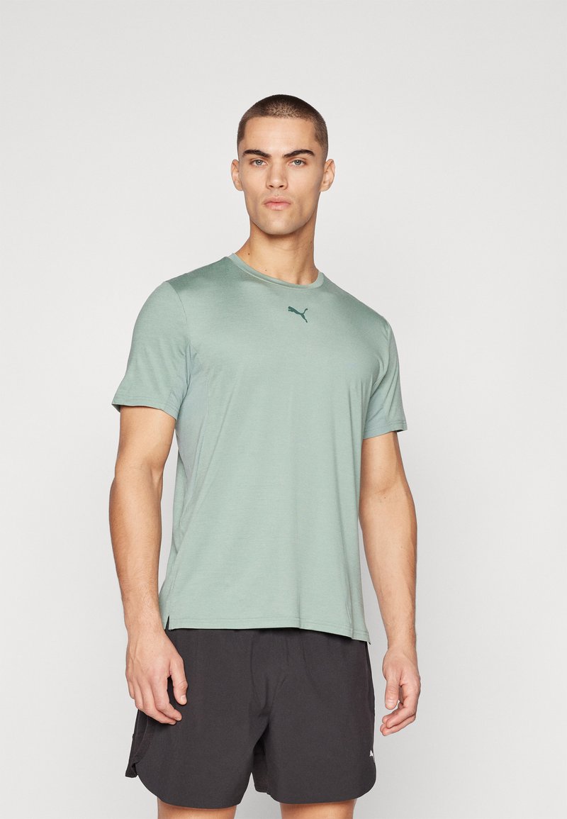 Puma lühikeste varrukatega spordit-särk helesinises, ümara kaelusega ja rinna peal diskreetse logo detailiga. Sile kangas.