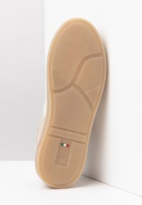 Beige rubber sneaker outsole with textured grip pattern and embossed logo; includes Italian flag detail and size 37 indicator.