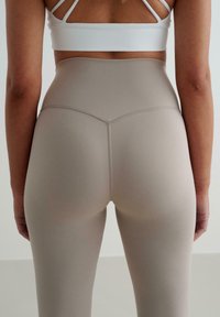 Högmidjade, sömlösa leggings i ett ljusbeige tyg, med en avsmalnande design och subtila sömmar längs yoken och sömmarna.