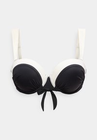 Μαύρο και λευκό επενδεδυμένο σουτιέν με ρυθμιζόμενους λευκούς ιμάντες και μαύρη λεπτομέρεια φιόγκος στο κέντρο μπροστά.