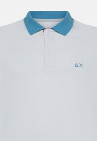 Polo in grigio chiaro con colletto a coste di un blu chiaro. Presenta una chiusura con tre bottoni e un piccolo logo blu sul lato sinistro del petto.