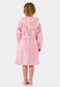Rosa kapuzen-Bademantel mit weichem Textil und kleinen weißen Punkten, am Taillenbereich mit einem Gürtel gerafft. Sichtbarer Saum auf Wadenhöhe.