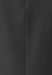 Tejido negro con una textura suave y un ligero brillo. Presenta una costura central que transcurre verticalmente para añadir un detalle de diseño.