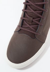Baskets marron avec languette en tissu, lacets assortis, dessus en cuir cousu et semelle en caoutchouc blanche vues de dessus, angle avant.