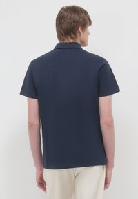 Polo a maniche corte di colore navy con colletto, realizzato in tessuto liscio; design semplice, senza motivi o decorazioni visibili sul retro.