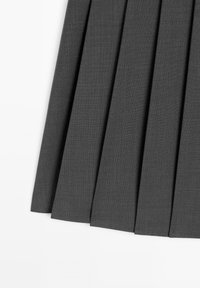 Section de jupe en tissu plissé gris foncé présentée sur fond blanc, mettant en avant des plis verticaux espacés uniformément.