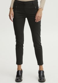 Čierne, slim-fit nohavice so zipsovými vreckami, vyrobené z elastického materiálu. Majú hladkú textúru a skrátenú dĺžku nad členkami.