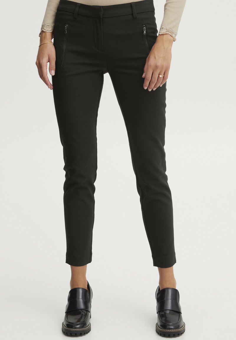 Čierne, slim-fit nohavice so zipsovými vreckami, vyrobené z elastického materiálu. Majú hladkú textúru a skrátenú dĺžku nad členkami.