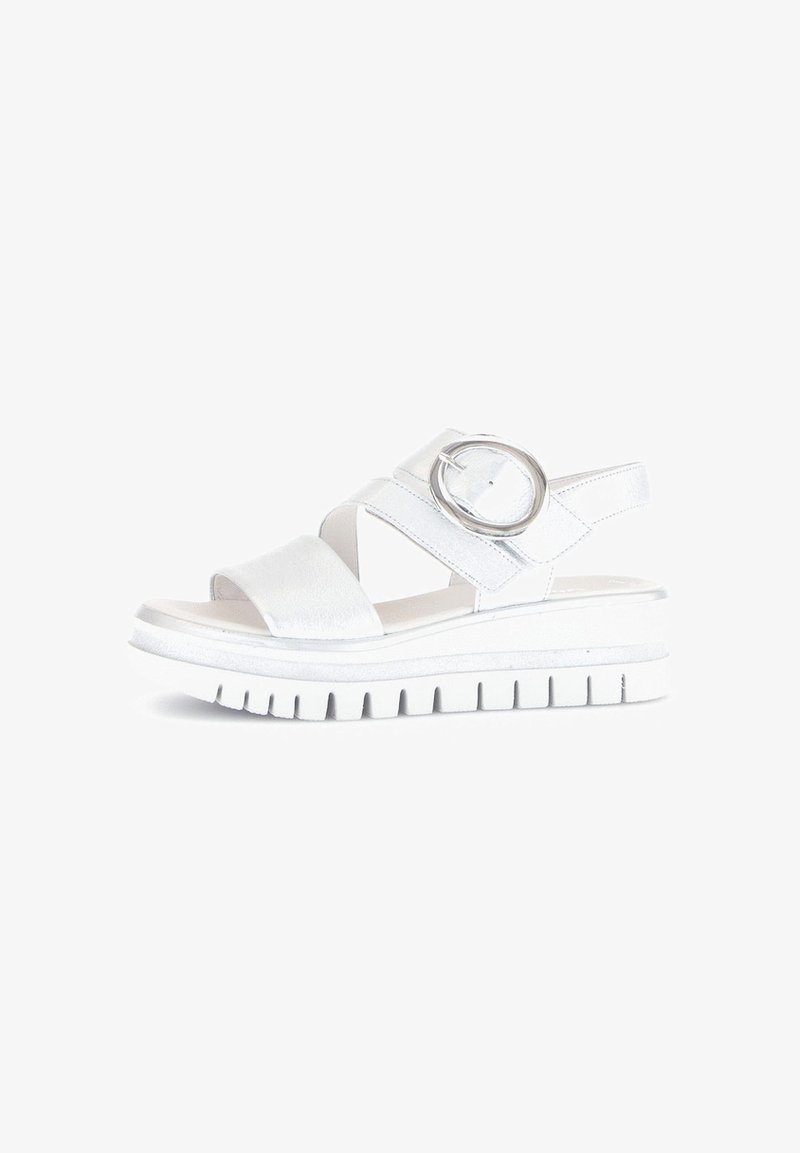 White platform sandals with two wide straps and a circular metallic accent. Smooth texture, rubber sole with a ridged pattern.