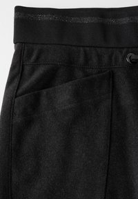 Pantalones de tela negra con una textura suave, cintura elástica y cordón. Presentan un bolsillo lateral cosido con un acabado limpio.