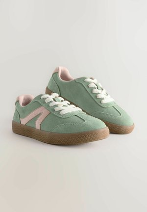 Grüne Wildledersneaker mit rosa Akzenten, weißen Schnürsenkeln, einer strukturierten Gummisohle und einem sportlichen Design, das ein markantes seitliches Logo-Detail aufweist.
