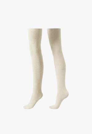 Calcetines hasta la rodilla en crema, con un patrón de punto texturizado y un borde ribeteado. Material suave, superficie lisa y diseño ajustado.
