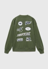 Felpa verde oliva con diverse stampe grafiche bianche, tra cui testo ed emblemi legati a "New York" e temi sportivi.