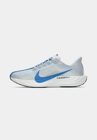 Svjetlo sivi i plavi Nike ZoomX trkački model s mrežastim gornjim dijelom, plavi swoosh, bijelim amortizirajućim potplatom i vezanjem, bočni pogled na bijeloj pozadini.