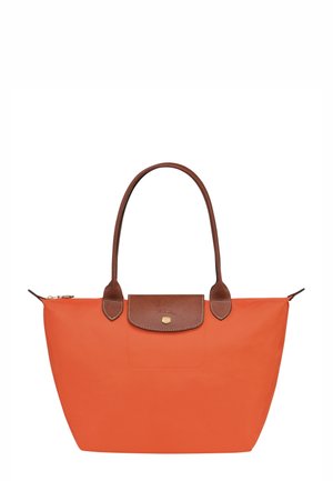Orange tote-taske med brune læderdetaljer, en glat tekstur og to robuste håndtag. Har en klaplukning med en guldlignende logo.